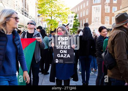 Freier palästinensischer Protest Exeter - maskierte Dame mit schwarz-weißem Schild "Ende der Belagerung des Gazastreifens" (palästinensische Solidaritätskampagne) Stockfoto