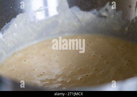 Ein Porträt eines Metalltopfes voller flüssigem belgischem Waffelteig, hergestellt aus einer Mischung aus Zucker, selbsterziehender Blume, etwas Salz und Eiern. ich bin einsatzbereit Stockfoto