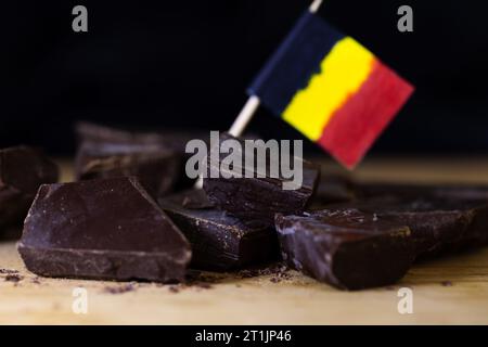 Ein Nahporträt einiger grober geschnittener Stücke leckerer brauner, dunkler belgischer Schokolade, die auf einer hölzernen Oberfläche liegen, mit etwas verschwommener belgischer Schokolade Stockfoto