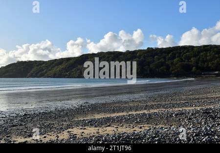 Blick entlang der Oxwich Bay auf die Hügel mit Bäumen, sowie die Felsen und Sand am Strand an einem sonnigen Oktobertag auf Gower in Südwales Stockfoto