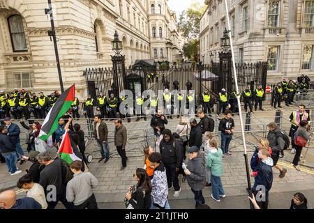 London, Großbritannien. 14. Oktober 2023. Polizisten vor der Downing Street als Unterstützer Palästinas bei einer Solidaritätsdemonstration von Portland Place nach Whitehall. Am 7. Oktober führte die Hamas einen überraschenden Mehrfrontenangriff aus Gaza auf Israel aus, und als Reaktion darauf hat der israelische Premierminister Benjamin Netanjahu erklärt, dass Israel im Krieg ist. Die Polizei hat gewarnt, die Flagge zur Unterstützung der Hamas zu führen, ist eine Straftat, die zu einer Verhaftung führen wird. Quelle: Stephen Chung / Alamy Live News Stockfoto