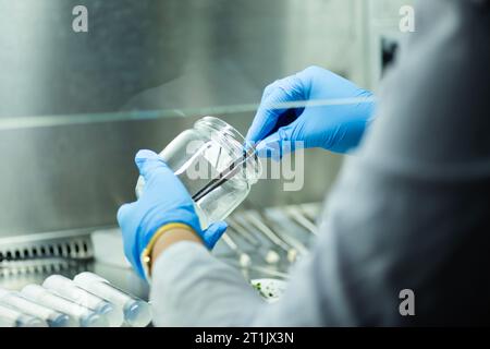 Ein Wissenschaftler, der in einem Labor arbeitet und Agrarforschung durchführt und ein Gefäß hält, um Proben zu entnehmen Stockfoto