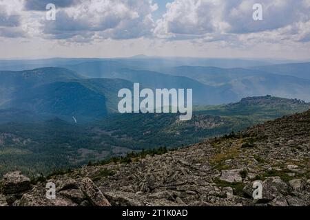 Die Sonnenstrahlen brechen durch die Wolken und erhellen die Felsen und den grünen Wald. Natürliche Landschaft am Sommertag. Wanderwetter. Lange Reise in einer Natio Stockfoto