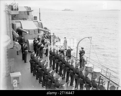 Die Royal Navy während des Zweiten Weltkrieges die Royal Marine Guard stellt die Arme als König George VI. an Bord der HMS DUKE OF YORK kommt bei einem Besuch der Home Fleet. Zwei der Schiffe 5,25 Zoll Geschütztürme im Hintergrund gesehen werden kann. Stockfoto