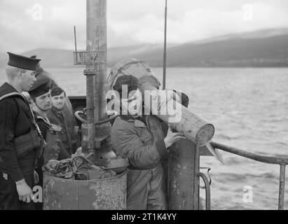 Die Royal Navy während des Zweiten Weltkriegs ein British Naval bewaffneten Guard als einem deutschen U-Boot Bewertung trägt Torpedo Teile aus übergeben U 826 am Loch Eriboll, Schottland als Deutschlands U-Boot Flotte ihre Hingabe an die Kräfte der Royal Navy begann. Stockfoto