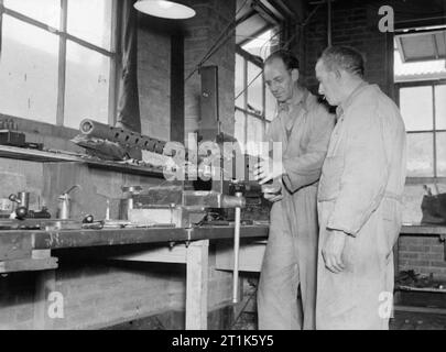 Leben an der Königlichen Marine Rüstung Depot Priddy ist hart, Gosport, 25-30 Juli 1944 In teh gunwharf von RNAD Priddy ist hart, Gosport, ein dobinson von Gateshead-on-Tyne, Ex-chef Waffenschmied, war 22 Jahre in der Marine (rechts) zeigt Henry Baker, Hastings, Trainee, wie ein Colt .5 für Fleet Air Arm verwenden zu montieren. Stockfoto