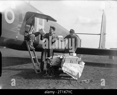 Royal Air Force Bomber Command, 1939-1941. Boden Besatzungsmitglieder hand Propaganda Merkblätter, die ein Besatzungsmitglied von Armstrong Whitworth Whitley Mark V, N 1386 "Y-P', der Nr. 102 Squadron RAF in Driffield, Yorkshire, vor einer Broschüre - Fallenlassen ('Nickelling') sortie über Deutschland. Stockfoto