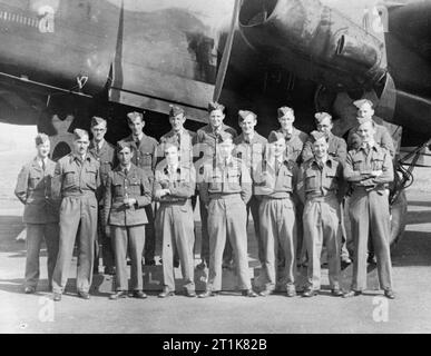 Royal Air Force Bomber Command, 1939-1941. Flying Officer Leonard Cheshire, während seine zweite Tour von Operationen mit Nr. 35 Squadron RAF dienen, steht mit seiner Luft- und Bodencrews vor einem Handley Page Halifax in Linton-auf-Ouse, Yorkshire. Stockfoto
