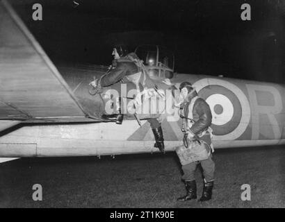 Royal Air Force Fighter Command, 1939-1945. Ein Pilot, (Flying Officer L G H Kells; links) und gunner von Nr. 29 Squadron RAF Klettern an Bord ihrer Bristol Blenheim kennzeichnen, wenn sie für eine Nacht sortie von coleby Grange/Wellingore Heath, Lincolnshire. Stockfoto