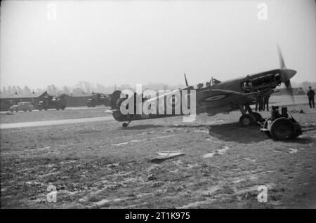 Royal Air Force Fighter Command, 1939-1945. Bodenpersonal läuft ein Motor prüfen auf einer Supermarine Spitfire Mark VB von Nr. 64 Squadron RAF in Hornchurch, Essex, bevor es sich für eine Schleife über Frankreich. Vier Ground Crew, die auf dem Schwanz sitzen, halten Sie das Flugzeug, während im Cockpit, ein Motor Monteur die Gassteuerung erhöht. Stockfoto