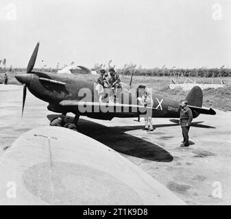 Royal Air Force im Nahen Osten, 1944-1945. Ein Pilot, unter Training für taktische Aufklärung Aufgaben, Blätter Supermarine Spitfire PR Mark IV, BR 416 "X", der Nr. 74 Betriebliche Ausbildung Bei Petah Tikva, Palästina, nach einem Ausbildungsflug. Ein korporal gesehen werden kann, durch eine Luke auf der Backbordseite, eine Zeitschrift der belichtete Film von einem Typ F24 Kamera senkrecht positioniert hinter dem Cockpit. BR 416 war ein Veteran fotografischer Aufklärer mit Nr. 1 Fotografische Reconnaissance Einheit im Vereinigten Königreich und auch mit der Nr. 680 Squadron RAF in der Romantik Stockfoto