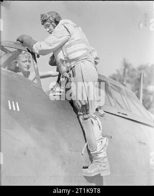 Royal Air Force in den Fernen Osten, 1941-1945. Flight Sergeant R Standish Wanderer von Woodford, Essex, einem Pilotprojekt mit Nr. 135 Squadron RAF dienen, steigt in seiner Republik Thunderbolt Mark I in Chittagong, Indien, von führenden Aircraftman R Rainford von Oldham, Lancashire besucht. Walker trägt seine Tropischen Überleben Anzug ('Beadon suit'), Mae West, und ist mit einem Dschungel Messer und Schraubendreher in einem Bein Scheide.. Stockfoto