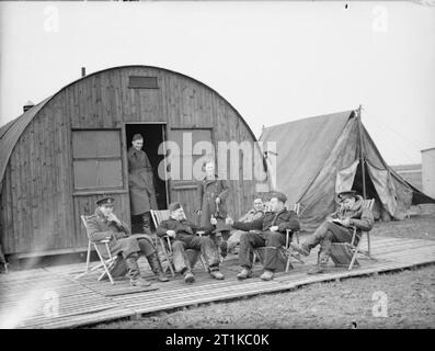 Royal Air Force - Frankreich, 1939-1940. Piloten von Nr. 607 Squadron RAF entspannen außerhalb Ihrer Crew Zimmer in Vitry-en-Artois. Diese ermittelten gehören Pilot Officer P L Parrott (erste links), Flying Officer W F Blackadder (Zweiter von rechts) und Flying Officer W E Gore (erste Straße rechts). Blackadder und der Offizier, mit denen er den Austausch von ist ein "Daumen hoch" sind noch in der Pre gekleidet - Krieg Royal Auxiliary Air Force blauen Overalls mit der Staffel Abzeichen auf der Vorderseite prangt links Taschen. Stockfoto