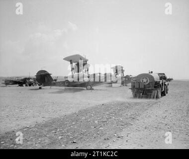 Royal Air Force - Italien, Balkan und Südosteuropa, 1942-1945. Supermarine Walrus Mark ist von 'C' Flug Nr. 293 Geschwader RAF Detachment, am Boden in Nettuno, Italien: X9506 ?C? Vor dem R6547 ?X? Geparkt wird. Im Vordergrund besprengt ein amerikanischer Wasserbogger die Oberfläche des Landeplatzes, um den Staub zu unterdrücken. Hinter den Walrossen werden die Supermarine Spitfire Mark IXs von No. 93 Squadron Detachment repariert und gewartet. Stockfoto