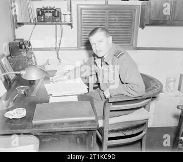 Royal Air Force - Italien, auf dem Balkan und in Südosteuropa, 1942-1945. Air Vice Marshal R M Fördern, Kommandierender Offizier der Wüste Luftwaffe, in seinem Büro Anhänger an DAF Advanced Hauptquartier in Cesena, Italien sitzen. Stockfoto