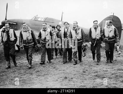 Die polnische Luftwaffe in der Schlacht um Großbritannien Eine Gruppe von Piloten der No. 303 Polnischen Jagdgeschwader, die von einem Hawker-Hurrikan auf die Kamera zugingen, nachdem sie angeblich von einem Jagdflugzeug zurückgekehrt waren. Von links nach rechts, in der ersten Reihe befinden sich: Pilot Officer Miros?aw Feri?; Flug Leutnant John A Kent (Kommandant des A-Fluges); Flying Officer Bogdan Grzeszczak; Pilot Officer Jerzy Radomski; Pilot Officer Witold?okuciewski; Pilot Officer Bogus?aw Mierzwa (verdeckt von?okuciewski); Flying Officer Zdzis?aw?aw?aw?Hennegowski; Flying Officer und Sergeant Eugeniusz Szaposznikow. In der Mitte, zum R Stockfoto