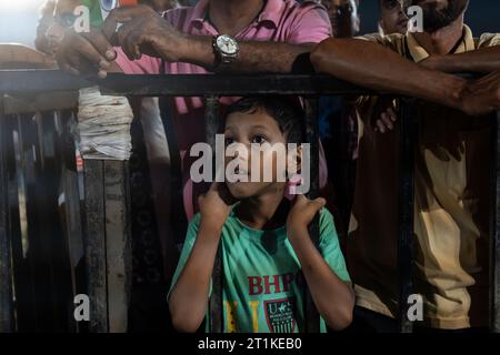 Indische Cricket-Fans bejubeln, als sie am 14. Oktober 2023 in Guwahati, Assam, Indien das One-Day International (ODI)-Spiel der ICC-Männer-Cricket-Weltmeisterschaft 2023 auf einer Projektionsleinwand in einem Feld anschauen. Indien besiegte Pakistan mit sieben Wickets. Quelle: David Talukdar/Alamy Live News Stockfoto