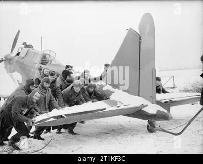 Royal Air Force - Frankreich, 1939-1940. Flieger von Nr. 226 Squadron RAF präsentieren fröhliche Gesichter für die Fotografen und gleichzeitig einer ihrer Fairey Schlachten durch den Schnee zu seinen Hangar in Reims. Stockfoto