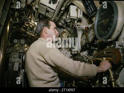 An Bord Hm-U-Boot Tribüne, 1942 Der zweite STEUERMANN von HMS TRIBÜNE, Petty Officer Hedley Charles Woodley auf seine Tauchbasis auf dem Vorwärts hydroplanes. Die tiefenlehre an das Foto zeigt, dass das U-Boot ist auf der Oberfläche. Das Foto wurde deshalb während der Dreharbeiten zu dem Film "Hautnah". Stockfoto