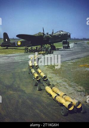 Ein Bombenzug mit 24 250lb Bomben, die von den wartenden Royal Air Force Panzern in einen en:Short Stirling Bomber] (s/n N6101) der No. 1651 Heavy Conversion Unit in Waterbeach, Cambridgeshire (UK) geladen werden. N6101 war einer der ersten Stirling, die Short and Harland in Belfast gebaut hatte. Stockfoto