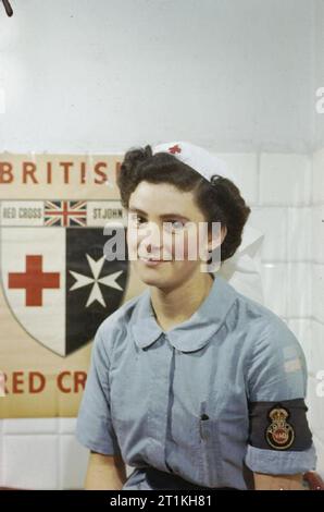 Frauen im Krieg 1939 - 1945 Krankenpflege: Brustbild der Krankenschwester Diana Hotham der Freiwilligen Ablösung (VAD) in Italien. Im Hintergrund ist ein Britisches Rotes Kreuz Poster. Stockfoto