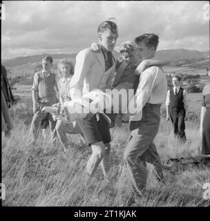 Co-operative Jugend Sommer Schulen - Bildung und Unterhaltung, Craig School, Windermere, England, Großbritannien, Juli - August 1943 eine Gruppe junger Leute, die die kooperative Union Summer School an Craig School, Lake Windermere, Praxis erste Hilfe bei einem Spaziergang auf der Hochmoore. Zwei Jungen tragen ein Mädchen, hat ihre Beine zusammen bandagiert, einer als Schiene für den anderen, "gebrochen", Bein verwendet werden. Die Erste Hilfe Kurse an der Summer School in Windermere wurden von Herrn F Kay der St. John Ambulance Feuerwehr geführt. Stockfoto