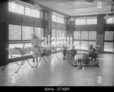 Kindertagesstätte an der Tottenham, London, England, 1940 Die sehr junge Kinder im Park Lane städtische Kindertagesstätte haben ihre eigenen Kinderzimmer. Hier schlafen Sie in Kinderbetten oder vergnügen sich im Laufstall. Stockfoto