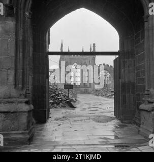 Coventry, Frühjahr 1944 - Alltag in Coventry, Warwickshire, England, Großbritannien, 1944 ein Foto von der Innenraum der Kathedrale von Coventry, die den Obdachlosen Shell des Kirchenschiffs, auf der Suche nach Chor, aus dem Westen Tür genommen. Ein Pfad durch den Schutt geräumt worden, und hinter einem Schild, ein Kreuz von verkohlten Dachbalken gemacht ist nur sichtbar auf der Website der Hochaltar. Stockfoto