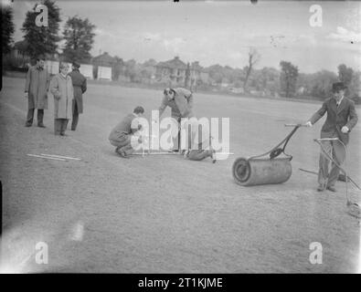 Cricket Match-Abdeckung von einer Übereinstimmung zwischen Kenton und Alexandra Park, Kenton, Middlesex, England, UK, 1945 Platzwarte kennzeichnen den Knick in Kenton Cricket Ground vor ihrem Match gegen Alexandra Park. Stockfoto