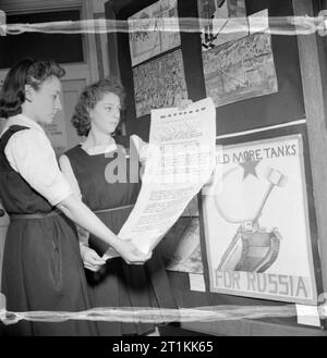 Ausstellung von Spielzeug für Russland, St Martin's School of Art, London, 1942 Patricia Collins und Joan Hayes (ab 15 Jahren) sind Monitore von Barnsbury County School in Woking. Hier sehen wir Sie halten eine Schriftrolle, auf der die Schule ihre Grüße an russische Kinder sendet. Die Grußansage wurde in Form einer Sonnet geschrieben wurden. Hinter ihnen, einer großen Tafel in Poster von Kindern aus anderen Schulen gezeichnet abgedeckt ist, alle Förderung der öffentlichen Russland zu unterstützen. Stockfoto