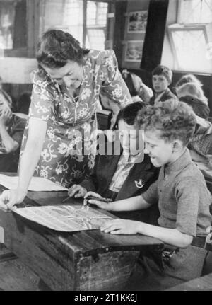 Ein Dorf speichert - die nationalen Ersparnisse in Lewknor, Oxfordshire, England, 1941 Frau Scott hilft zwei Schüler an der Dorfschule in Lewknor mit dem Poster sie Zeichnung für einen Wettbewerb der nationalen Ersparnisse Ausschuss organisiert sind. Das beste von diesen Plakaten nach London geschickt werden im Rahmen des Wettbewerbs beurteilt werden. Stockfoto