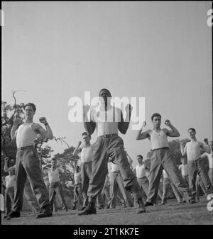 Erste US-Armee Rehabilitationszentrum - Erholung und Ausbildung bei 8 Erholungsheim, Stoneleigh Park, Kenilworth, Warwickshire, Großbritannien, 1943 Private David Brown (Mitte) und seine anderen B Grad Kollegen 'Star springt", sondern mit ihren Waffen versteckt, ihre Fäuste, neben ihrer Schultern, während einer körperlichen Training an 8 Erholungsheim, Stoneleigh Park. Private Braun (von 307 W. Holl Gassen, Savannah, Georgia) an ein Coca-Cola-Werk arbeitete vor dem Krieg, und erholt sich von einem leistenbruch Operation. Eine Besoldungsgruppe B Trainee, Braun ist fast wieder auf die volle Eignung: Sobald er ein gra erreicht. Stockfoto