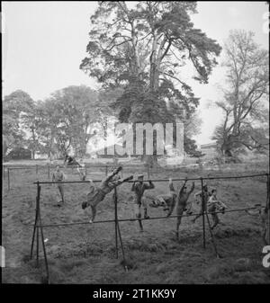 Erste US-Armee Rehabilitationszentrum - Erholung und Ausbildung bei 8 Erholungsheim, Stoneleigh Park, Kenilworth, Warwickshire, Großbritannien, 1943 Auszubildende bei der 8 Erholungsheim, Stoneleigh Park, der vor kurzem zu einer Besoldungsgruppe befördert wurden, testen Sie sich selbst, um zu sehen, wenn Sie wirklich voll sind. Hier sind Sie verhandeln über eine Reihe von Zäunen, die von den Teilnehmern als Teil eines längeren und schwierigen Parcours aufgebaut. Stockfoto