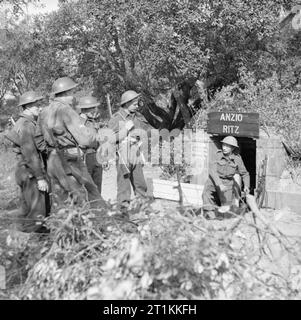 Die britische Armee in Italien 1944 Unterhaltung der Truppen: Kino war eine populäre Form der Erholung für Männer und Frauen in Uniform. Potenzielle Zuschauer (Corporal F Spink, Treiber EIN J Harvey, Sapper E Thomas, Sapper J Dymott, Treiber J Waite und Private H Gibson) sprechen Sie mit Corporal M A Moyse der Armee Kinematograph Service (AKS) am Eingang der &#145; Anzio Ritz&#146;, eine kleine &#147;Erdloch , kino &#148; für das Fünfte Armee erstellt die stark - geschält Anzio Brückenkopf in Italien, März 1944. Stockfoto