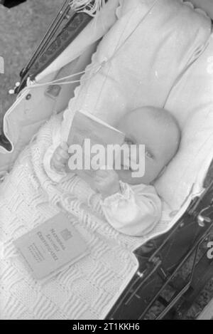 A Village Savings- National Savings in Lewknor, Oxfordshire, England, 1941 dieses kleine Baby John Andrew ist 6 Monate alt und ist sein Gewicht in Gold Wert, da er 18 kg wiegt und über nationale Sparzertifikate im Wert von 18 Pfund verfügt. Stockfoto