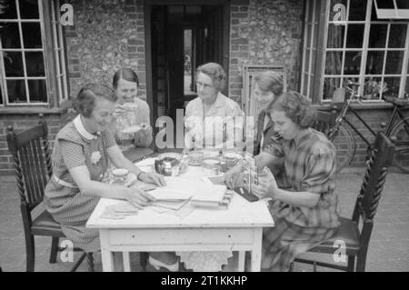 Ein Dorf speichert - die nationalen Ersparnisse in Lewknor, Oxfordshire, England, 1941 Damen der Lewknor Einsparungen Ausschuss für Kaffee in der Sonne vor dem Haus von einem seiner Mitglieder zusammen. Frau Scott, Frau Amor, Frau Bates, Frau Trimmen und ihre Kollegen jede konzentrieren sich auf den Verkauf von Einsparungen Briefmarken zu einer anderen Straße in das Dorf. Stockfoto