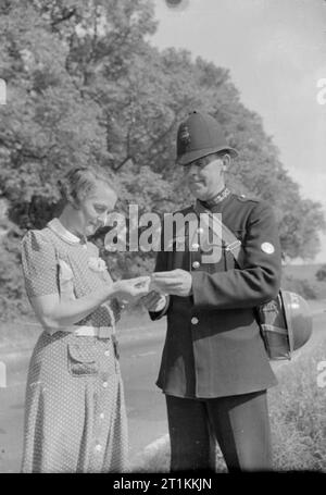 Ein Dorf speichert - die nationalen Ersparnisse in Lewknor, Oxfordshire, England, Village School mistress 1941, Frau Scott, verkauft Einsparungen Stempel für die lokalen Polizisten, PC Hufton, auf einem sonnigen Land Lane. PC Hufton ist ein Ex-Scots Guards. Stockfoto