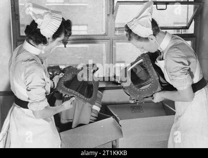 Gas Bohren in einem Londoner Krankenhaus - Gasmasken für Babys getestet, England, 1940 Krankenschwestern sind Einpacken baby gas Atemschutzmasken nach einem Bohrer an einem Londoner Krankenhaus, 1940. Stockfoto