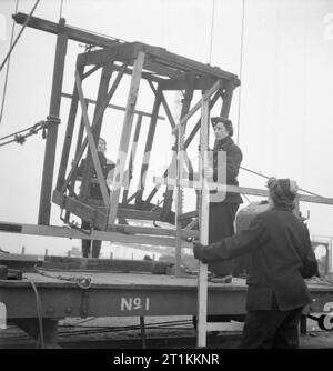 Mädchen Gunners - die Arbeit der Auxiliary Territorial Service auf eine experimentelle Station, Shoeburyness, Essex, England, 1943 ATS Frauen abbauen Geschwindigkeit Bildschirme bei Shoeburyness, nach einer Prüfung durch die Königliche Artillerie. Die Schalen sind durch die Bildschirme, die ein Raster aus Kupferdraht gefüllt worden war. Wenn die Shell ist durch den Draht abgefeuert, wird der Stromkreis unterbrochen, die Ergebnisse in der Geschwindigkeit, mit der die Geschwindigkeit des Shell überprüft werden können. Die Schalen wurden in das Meer bei Ebbe gefeuert. Stockfoto