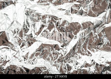 Die Textur der zerknitterten Silberfolie. Folie mit Dellen, Falten und Falten Stockfoto
