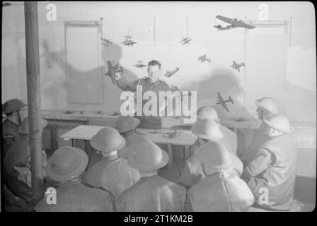 Home Guard Mann Anti Aircraft Gun - Zivilschutz in Großbritannien, 1943 Männer der Home Guard hören Sie einen Vortrag von einem Royal Artillery Sergeant auf, wie man feindliche Flugzeuge zu identifizieren. Modell Flugzeuge hängen gegen eine weiße Wand in den Identifikationsprozess Beihilfen gewaschen. Stockfoto