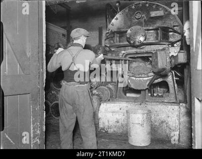 Küchenabfällen in Futtermitteln für Rinder - Bergung auf dem britischen Home Front, 1942 zubereitet und Flüssiggas Haushalt Abfälle werden aus dem Ofen in eine große metal bin durch eine Bergung Arbeiter an diesem Depot kratzten, irgendwo in Großbritannien. Das Fach wird als eine Form, in der die feuchten Botschaften in feed Kuchen verfestigen verwendet werden. Stockfoto