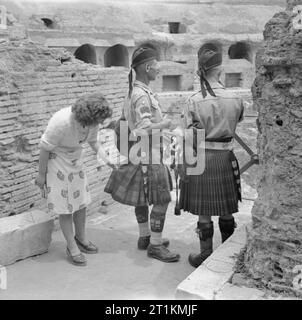 Die britische Armee in Italien 1944 eine italienische Frau prüft die kilts von Pipe Major William MacConnachie und Pipe Major William Boyd im Kolosseum von Rom, 6. Juni 1944. Stockfoto