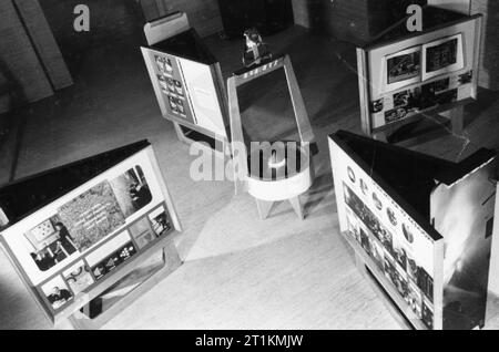 Afs-Ausstellung für New York, 1941 ein Foto, eine Ausstellung des Ministeriums für Informationen, die sich auf die Arbeit der Londoner Feuerwehr und die Feuerwehr, die nach New York verschifft werden. Die verschiedenen Elemente des Displays gehören 'Fortschritt eines Incident', die Arbeit der LFB und AFS im Notfall (links), "Nervenzentrum der Londoner Feuerwehr Hauptquartier Kontrollraum" (Rechts) und "Helden von London" (hinten rechts), die Portraits von verschiedenen Feuerwehrleute. Die Ausstellung ist im Foyer von MoI am Senat Haus eingerichtet worden. Stockfoto