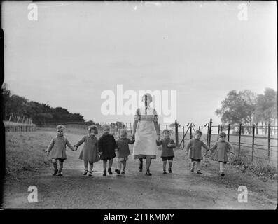 Leben an der tapley's Park Kinder Home (Chaim Weizmann Home), Instow, Devon, Oktober 1942 eine Krankenschwester und sieben junge Kinder genießen Sie einen Spaziergang auf dem Gelände des Chaim Weizmann Home an tapley Park in Instow, Devon. Über das Geländer und knapp über dem Horizont ist der Fluss Torrington. Stockfoto