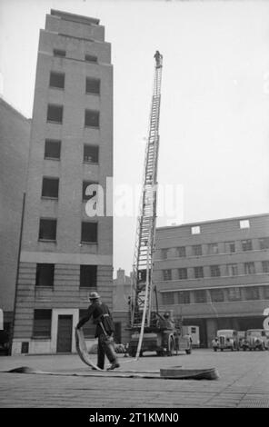 London AFS-Männer der Feuerwehr in London, C 1940 eine Drehleiter im Einsatz, die von den Mitgliedern der Feuerwehr bei einer Übung an der Londoner Feuerwehr Hauptquartier. Stockfoto