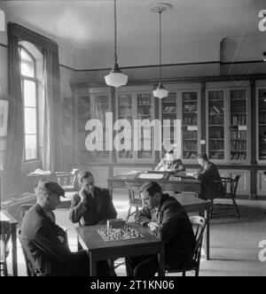 London ist die Seeleute Heim und Red Ensign Club, 1942 Seeleute lesen, schreiben und Schach in der ruhigen Umgebung der Bibliothek spielen bei der Londoner Merchant Seamen's Home und Red Ensign Club. George Lappin kann im Hintergrund gesehen werden, der sich auf der rechten Seite des Fotos, einen Brief schreiben. Stockfoto