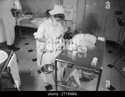 Herrenhaus wird Mutterschaft Startseite - Leben bei Brocket Hall, Welwyn, Hertfordshire, 1942 Student Krankenschwester bereitet ein Baby für eine Badewanne bei Brocket Hall. Die Krankenschwester ist das Tragen einer chirurgischen Maske die Ausbreitung von Keimen auf den Säugling zu vermeiden. Stockfoto