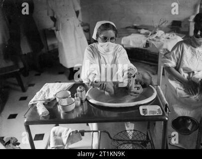 Herrenhaus wird Mutterschaft Startseite - Leben bei Brocket Hall, Welwyn, Hertfordshire, 1942 Student Krankenschwester Bäder ein Baby bei Brocket Hall. Die Krankenschwester ist das Tragen einer chirurgischen Maske die Ausbreitung von Keimen zu verhindern. Stockfoto