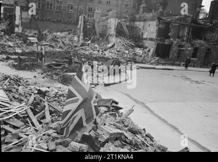 London zeigt die Flagge - Das Leben geht weiter in Kriegszeiten London, England, 1940 ein Union Flag sitzt stolz unter den Trümmern in einer Bombe beschädigt die London Street, nach einem Luftangriff. Stockfoto